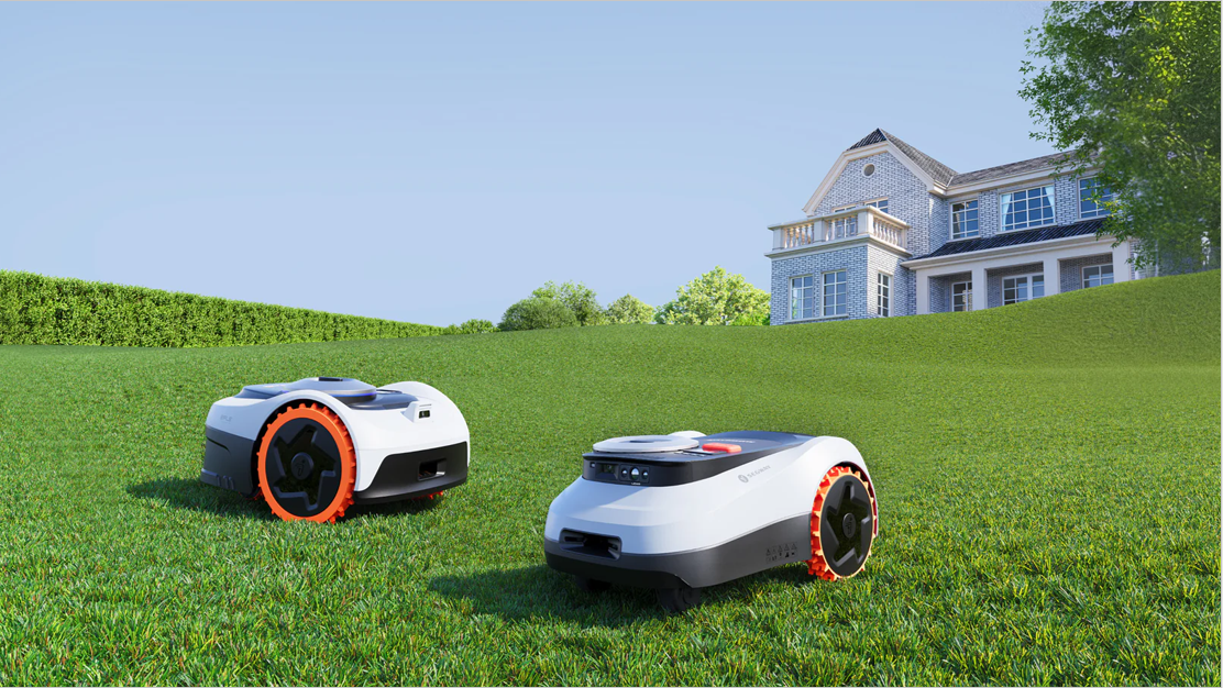 Två moderna kabelfria robotgräsklippare står redo på en stor gräsmatta framför en villa, vilket illustrerar den nya standarden för prisvärd trädgårdsteknik.