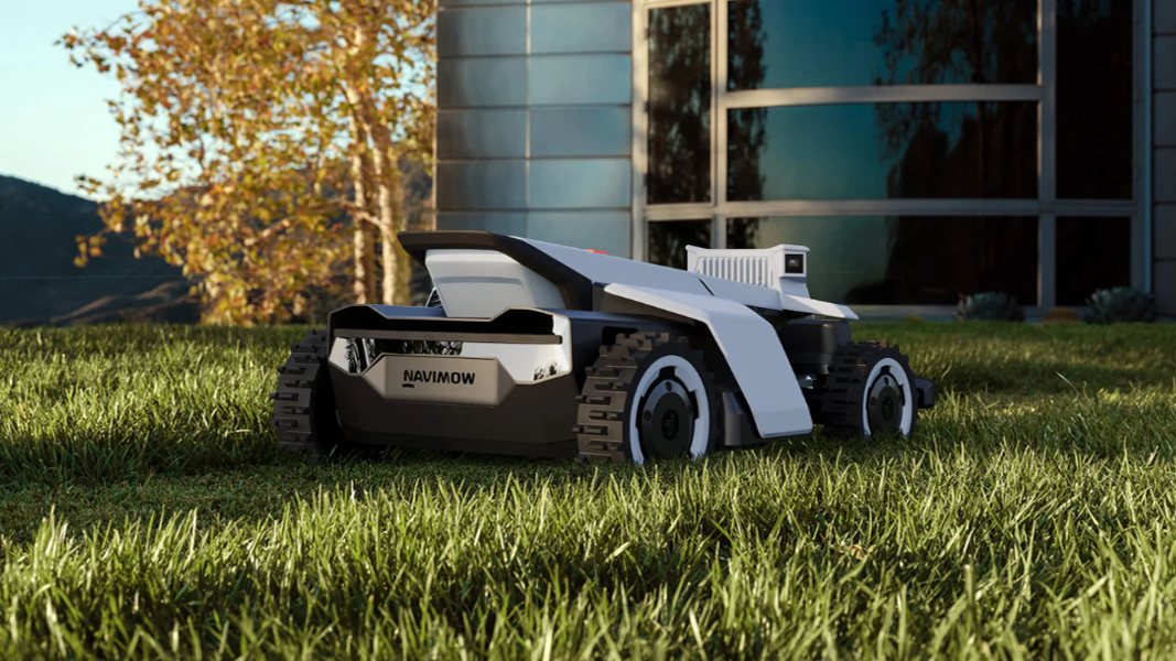 Navimow robotgräsklippare som arbetar på en välskött gräsmatta framför ett hus.