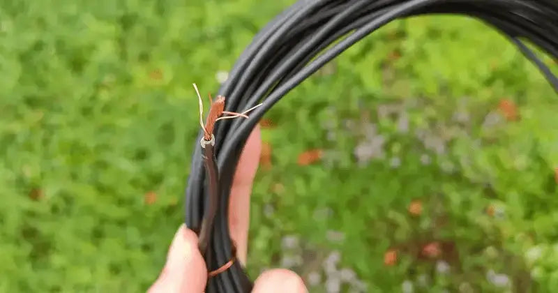 En avklippt begränsningskabel för robotgräsklippare med exponerad koppartråd.
