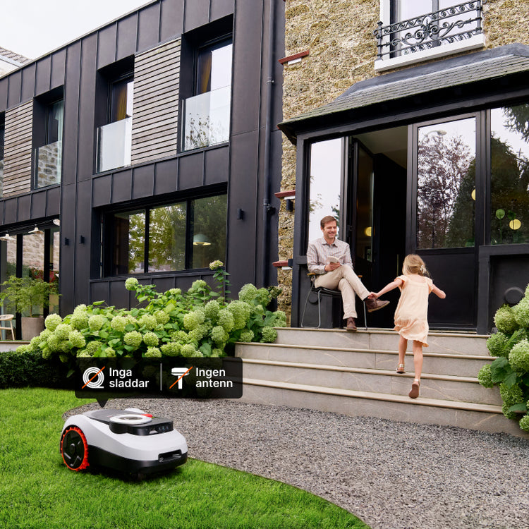 Navimow i105E robotgräsklippare klipper gräset framför ett stort modernt hus.