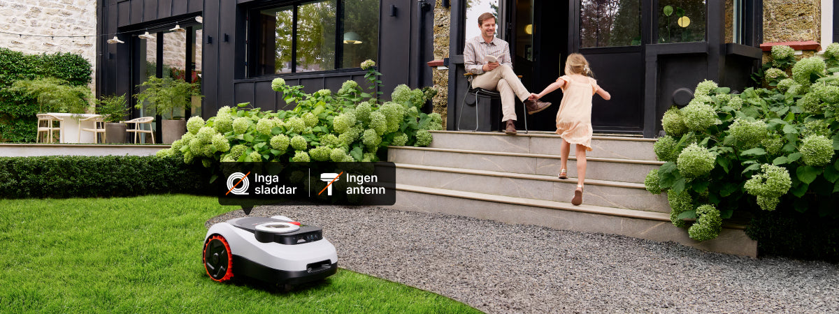 Navimow i105E robotgräsklippare klipper gräset vid ett hus i solsken.